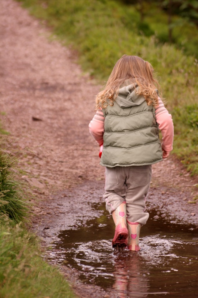 Little girl walking through mud puddle.