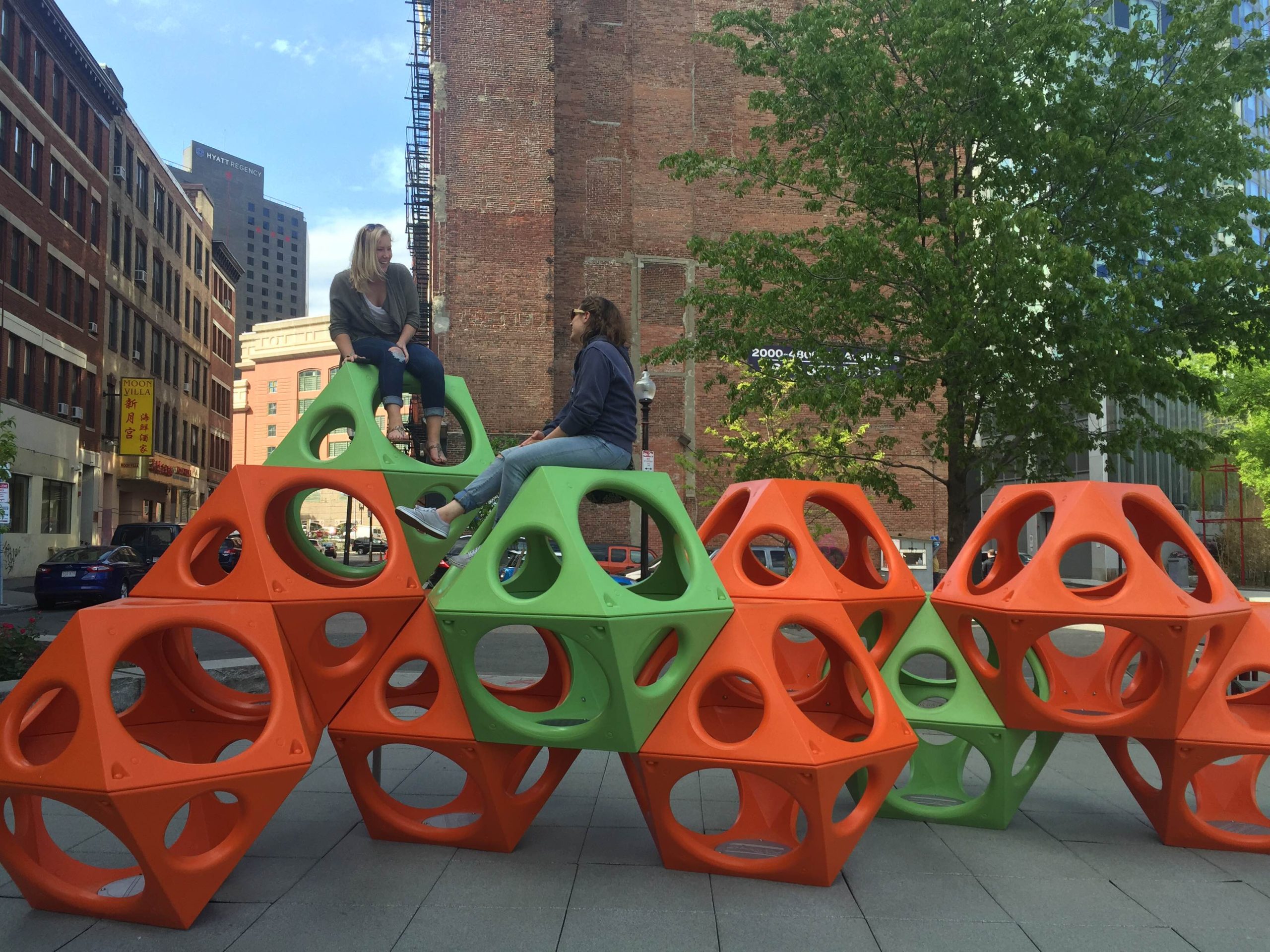 two women talking on green and orange playground climbers