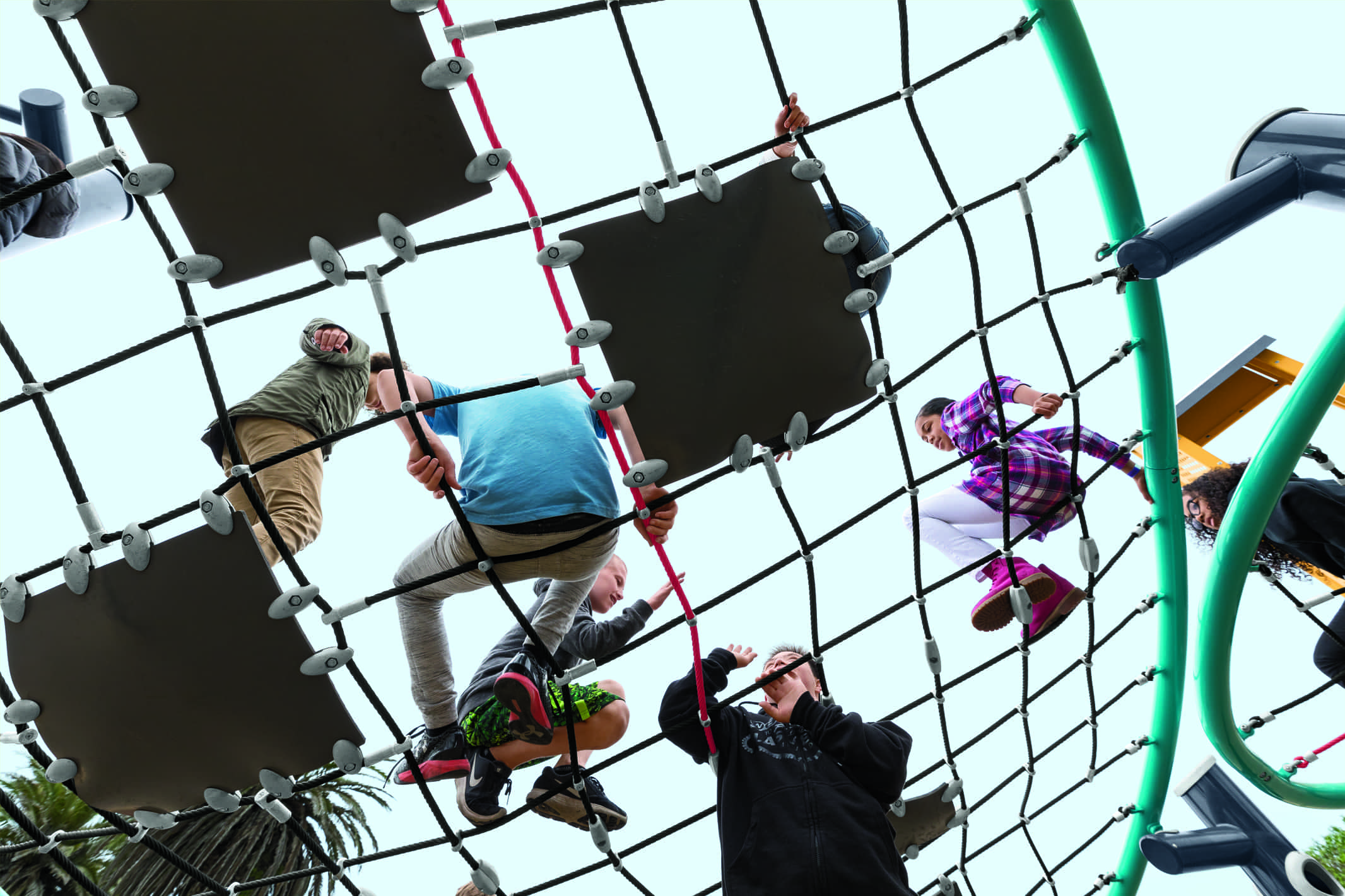 Kids climbing on a playground climber that has a net