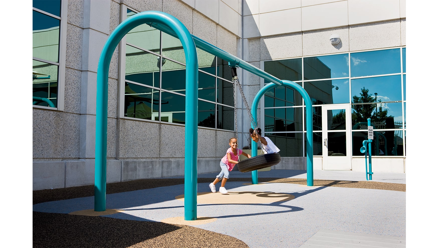 Two young girls swinging on a tire swing